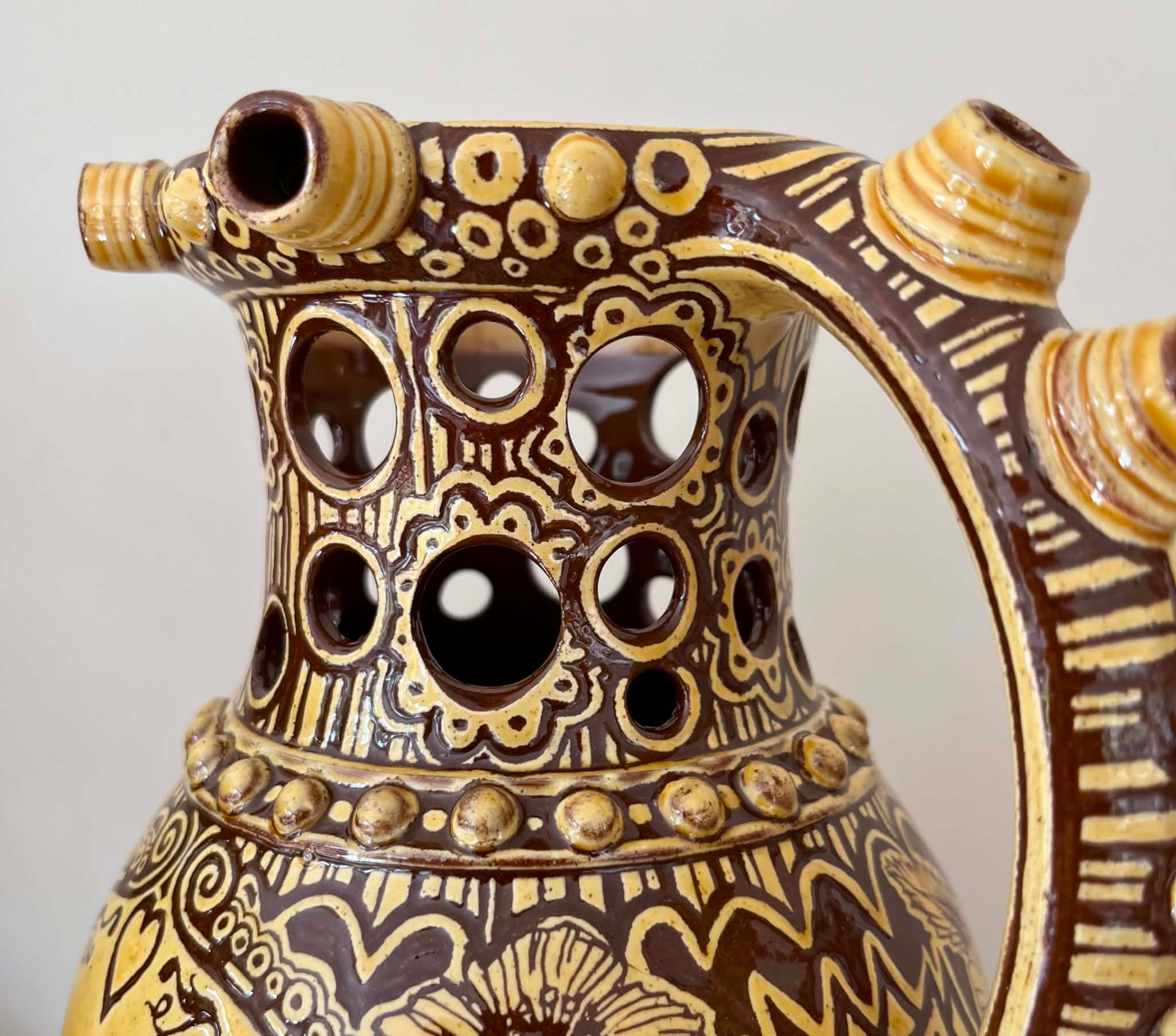 Close view of the finished jug's pierced neck, rim spouts and handle.