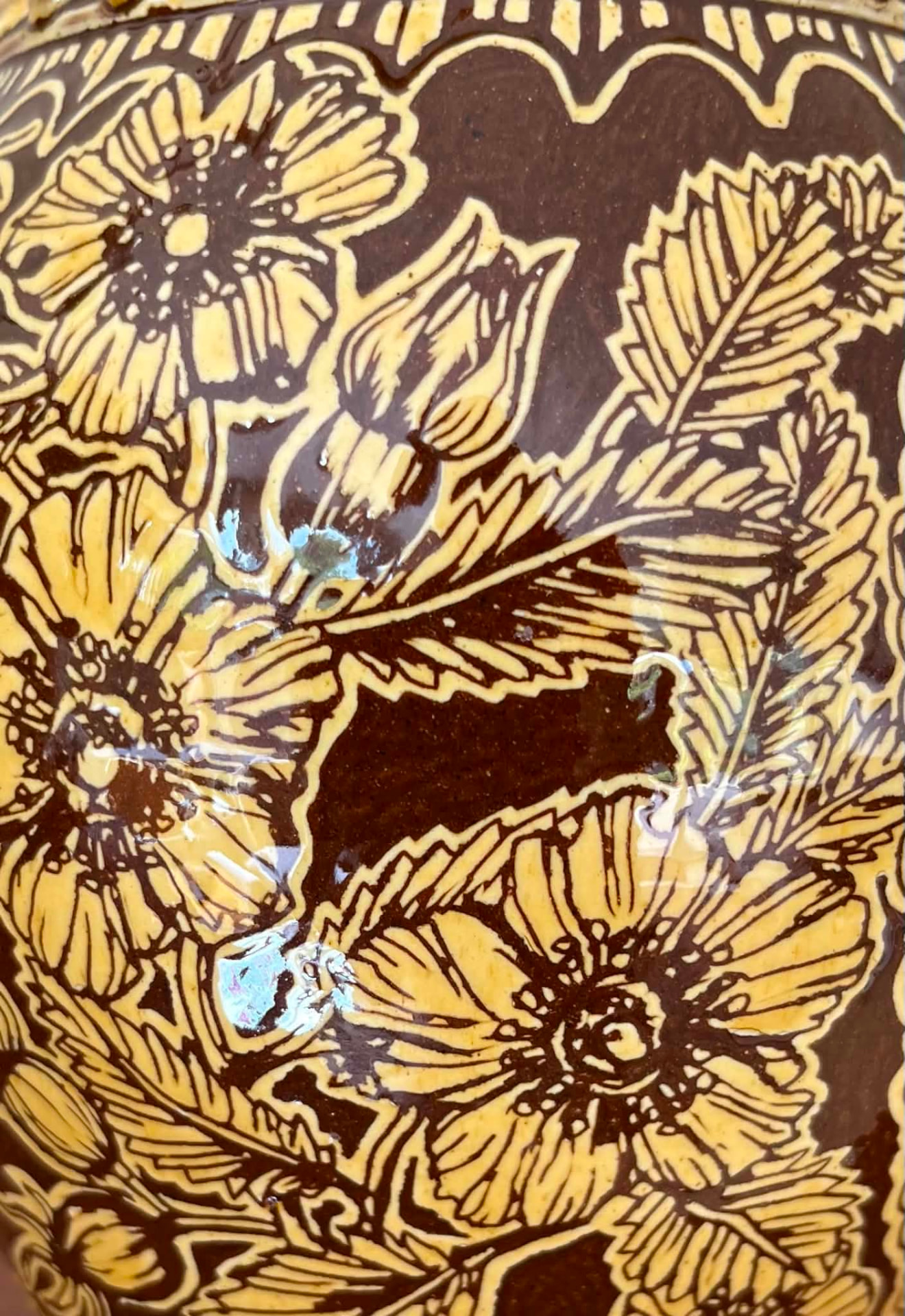 Close view of glazed flower and leaf sgraffito.